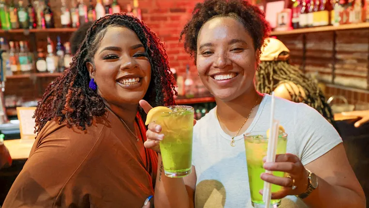 Two customers at the bar at Island Soul, smiling over cocktails.