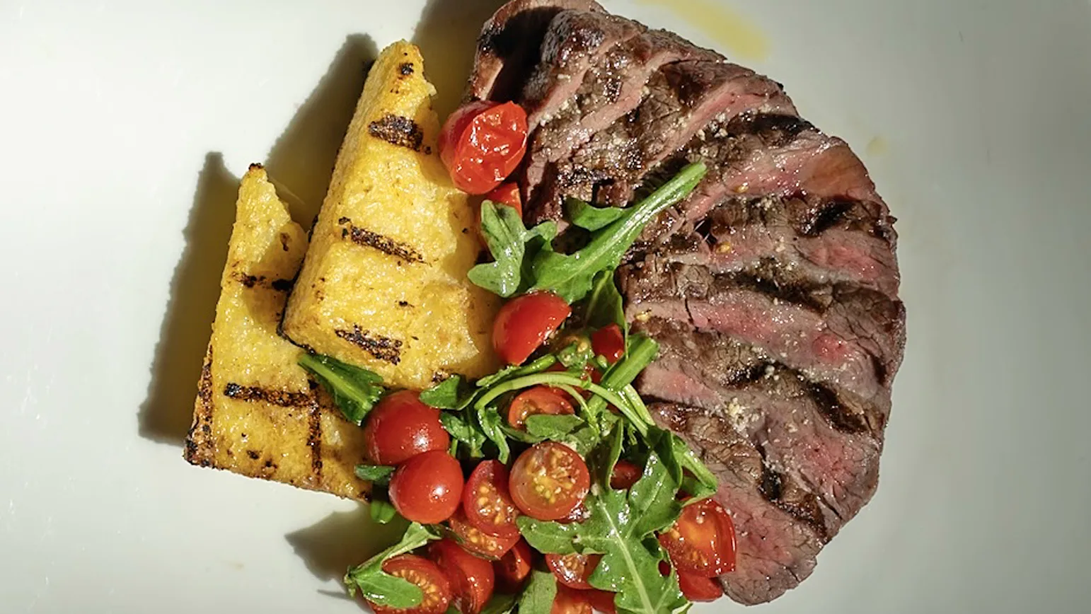 Tagliata filetto &mdash; sliced grilled beef fillet with grilled polenta wedges and an arugula and cherry tomato salad.