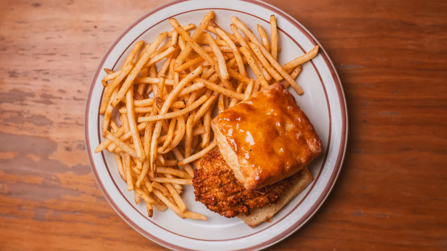 The Honey Butter Chicken Biscuit Sandwich: fried chicken on a glazed biscuit, served with a pile of thin fries.